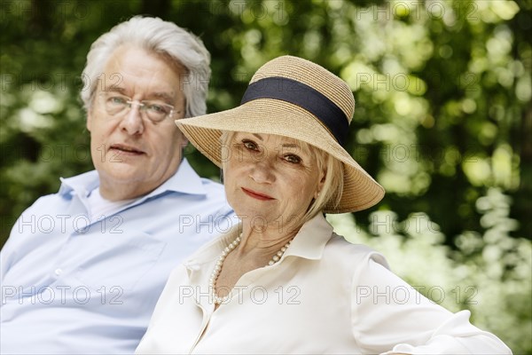 Summery dressed older woman together with her grey-haired man in the park