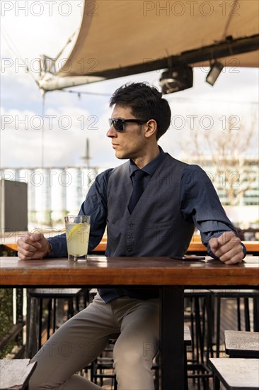 Businessman sitting at an outdoor bar drinking lemonade