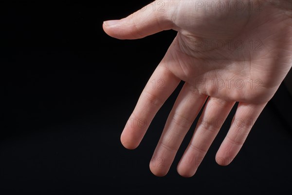 Five fingers of a child hand partly seen in black background