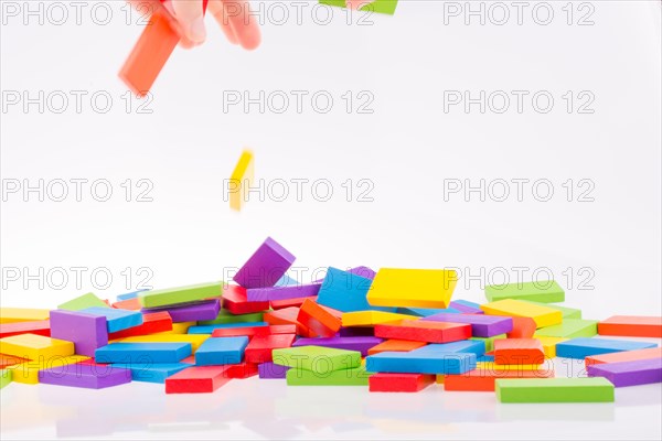 Hand playing with colored domino on white background