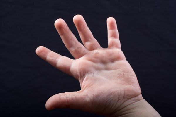 Five fingers of a child hand partly seen in black background