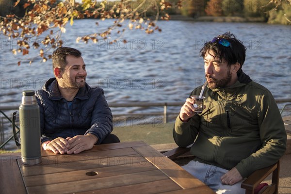 Two friends enjoying the sunset while drinking mate