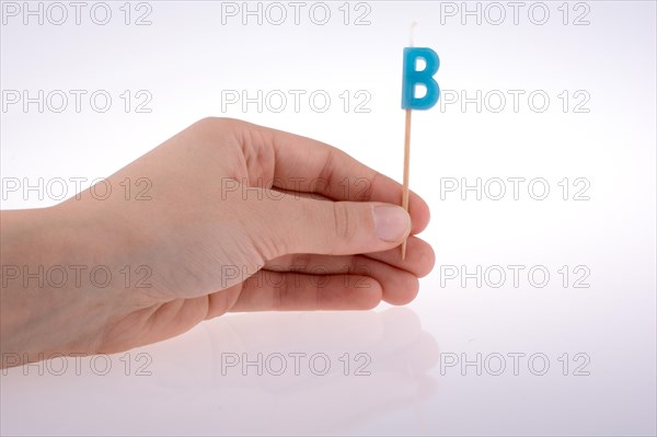 Color candle in hand on sticks writes the letter B