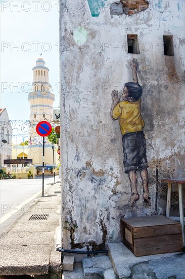 Street art Reaching Up on a wall in George Town on Penang Island