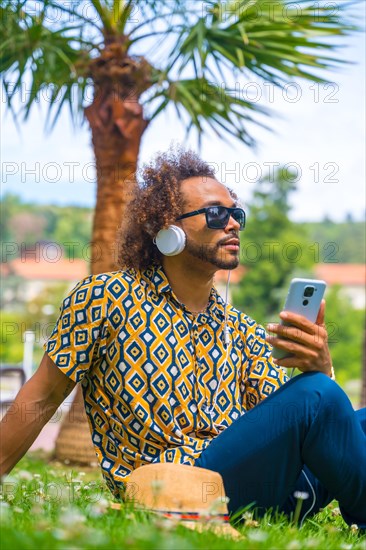 Afro-haired man on summer vacation next to some palm trees by the beach. Traveling and tourism concept