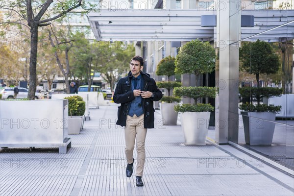 A businessman taking off the mobile phone from his pocket while walking in the street