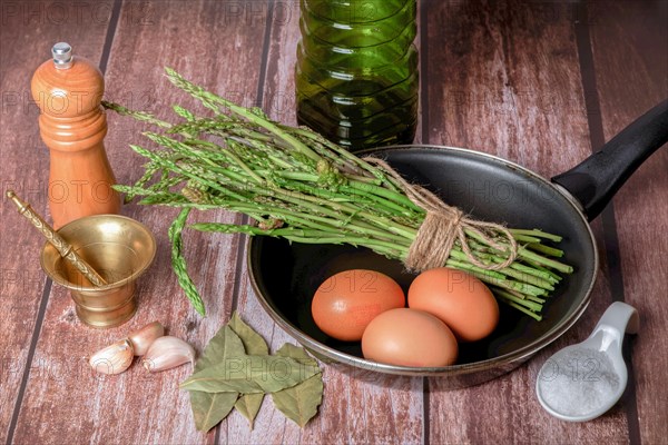 Bunch of wild asparagus in a frying pan with eggs