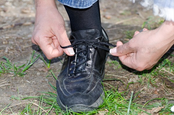 Woman Tying Shoelaces on a Path with Grass