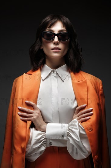 Spectacular beautiful woman in a trendy orange suit with classic make-up. Beauty face. Photo taken in the studio on a white background