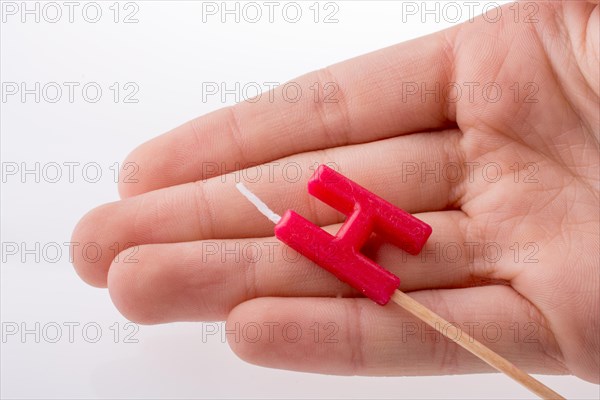 Color candle in hand on sticks writes the letter H