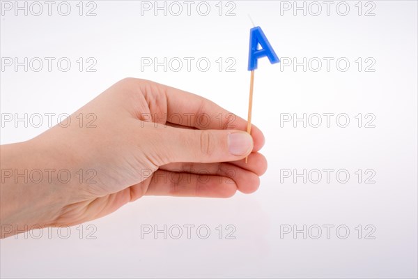 Color candle in hand on sticks writes the letterA