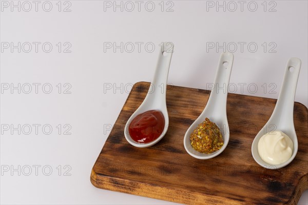 Spoons three sauces ketchup mayonnaise mustard white background