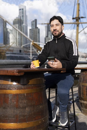 Latin tourist drinking coffee at an outdoor bar in Puerto Madero