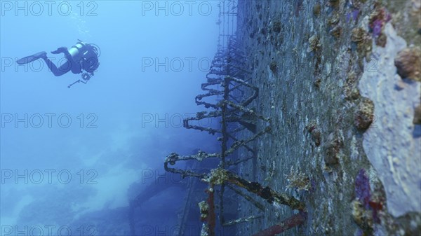 Scuba diver swim along deck of ferry Salem Express shipwreck approaching the ship's superstructure