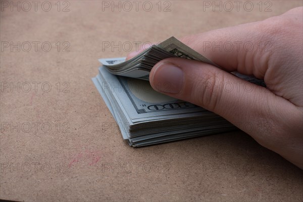 Hand holding banknote bundle of US dollar on a linen canvas background