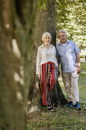 Summery dressed older woman together with her grey-haired man in the park