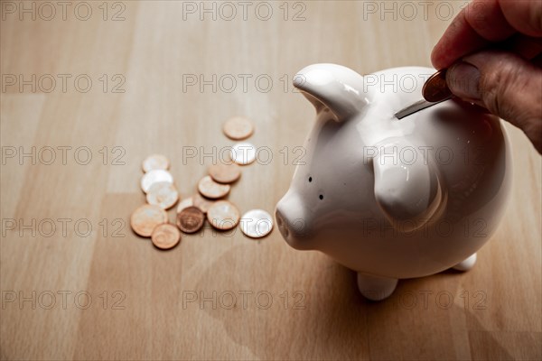 Male hand puts cent coin in piggy bank