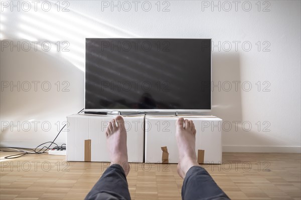 Television on Cardboard Box in Living Room and Men Legs in Switzerland