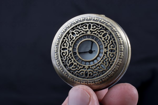 Retro style pocket watch in hand on black background