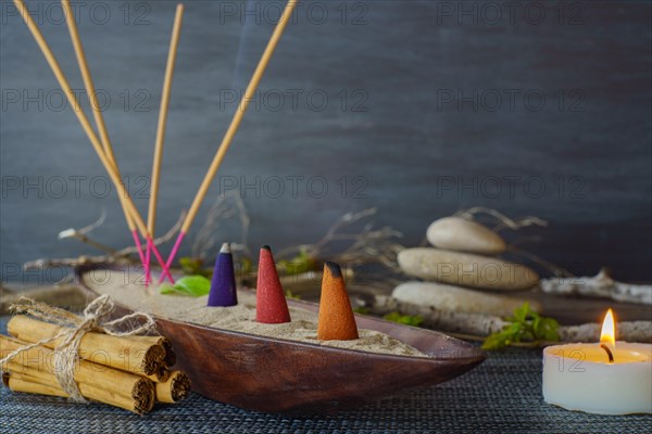 Various types of incense smoking in a wooden bowl with sand