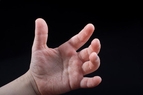 Five fingers of a child hand partly seen in black background