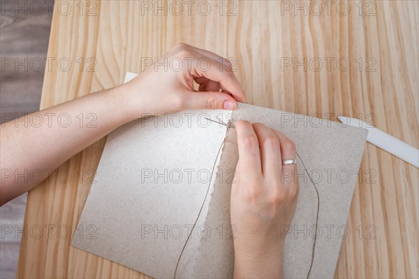 Close-up detail of woman's hands sewing a handmade notebook made in her workshop