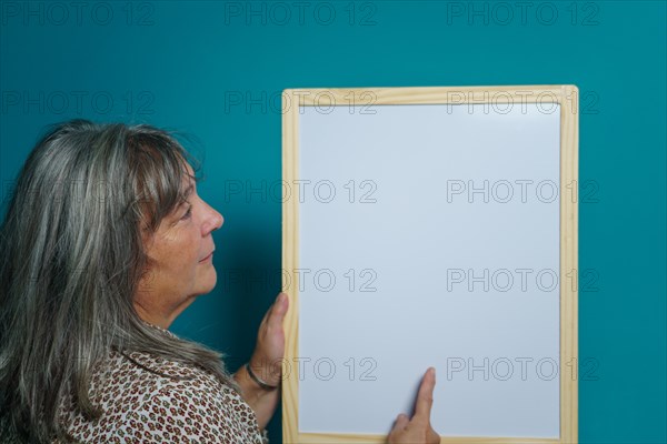 Older white-haired woman holding a white board to paste text on