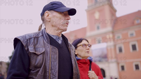 Elderly couple of tourists are walking through the historical center seeing the sights in an old European city. Palace Square