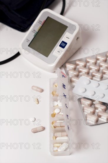 Daily pill box with blood pressure monitor in the background isolated on a white background