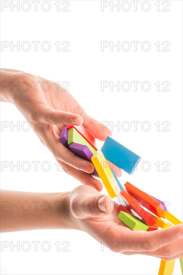 Falling colorful domino off hand on white background