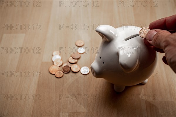 Male hand puts cent coin in piggy bank