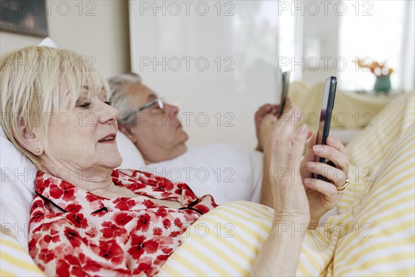 Elderly couple lying in bed together in their bedroom