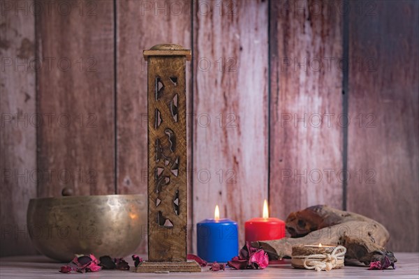 Wooden incense burner with colored candles and Tibetan bowl on a wooden background