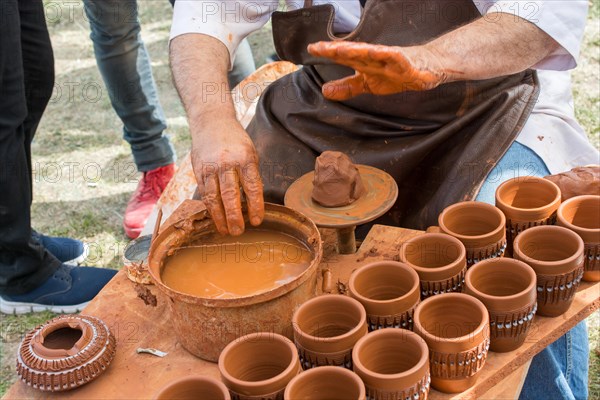 Potter`s hands shaping up the clay of the pot