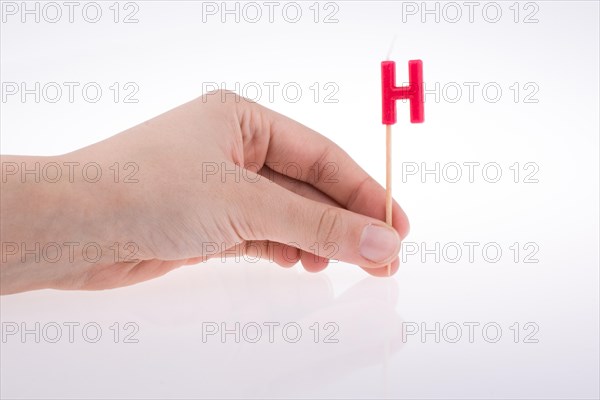 Color candle in hand on sticks writes the letter H