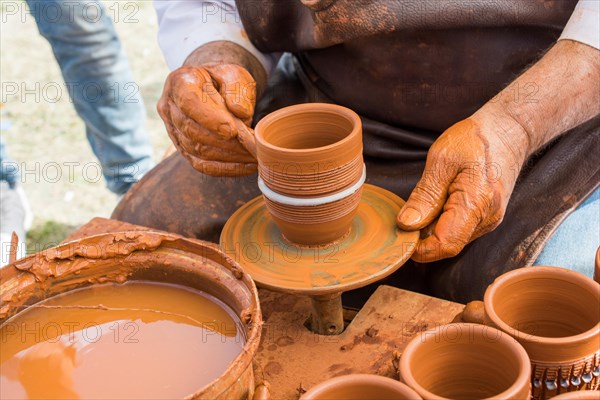 Potter`s hands shaping up the clay of the pot