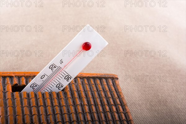 Thermometer measuring high temperature placed on a little model house