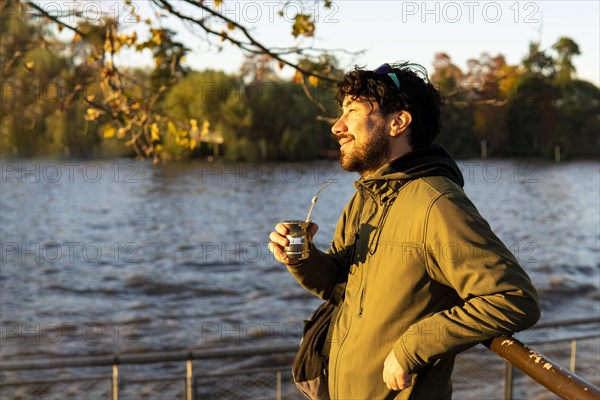 Latin man enjoying the sunset at the river while drinking mate