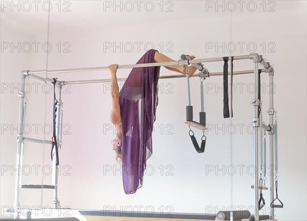 Woman Hanging Upside Down and Exercising on Pilates Machine