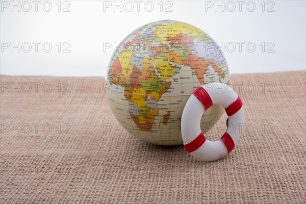 Life preserver beside a globe placed on canvas background