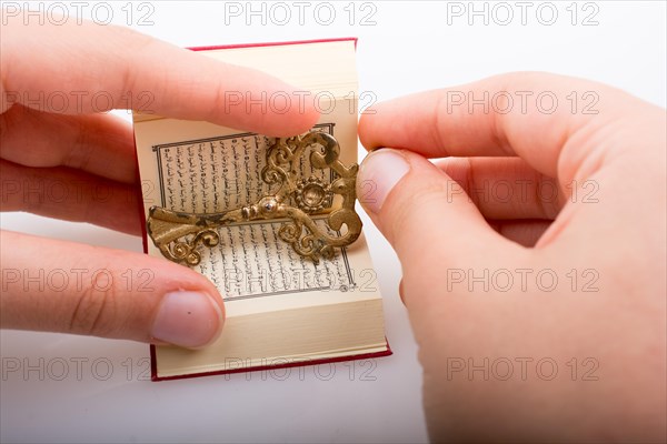 Hand holding Key and Islamic Holy Book Quran in mini size