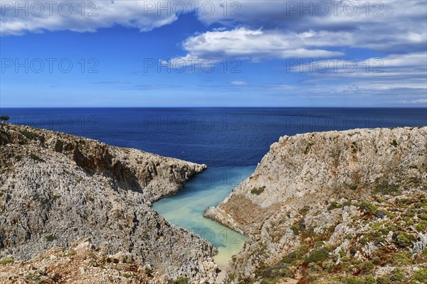 Beautiful view of z-shaped cove or lagoon in typical hills of Crete landscape. Clear blue sky and beautiful clouds on sunny day. Azure sea waters. Stefanou beach