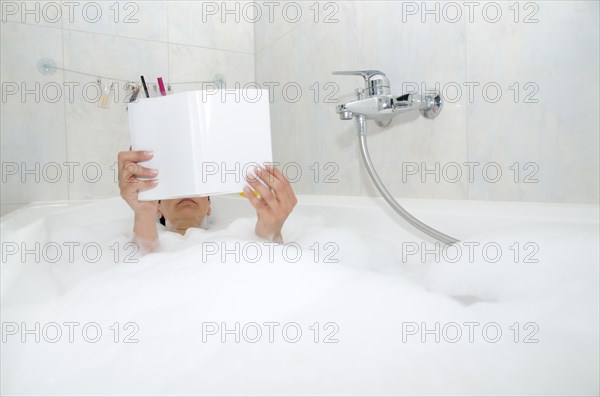 Woman reading a book in a bathtub with foam