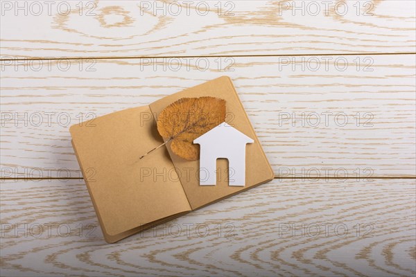 Little paper house on a notebook on parquet