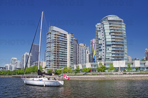 Small yachts with Canadian flag in front of skyscraper canyons