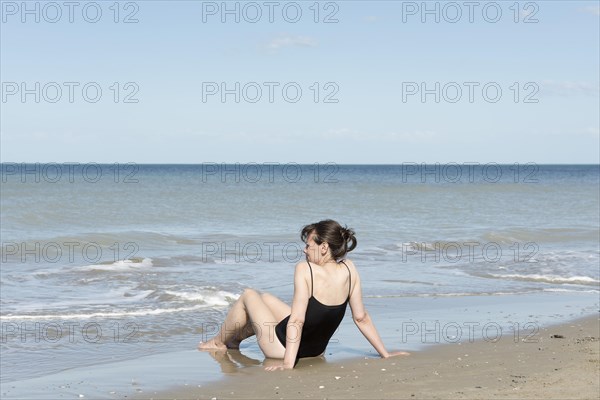 Woman Sitting on the Sand Beach with her Swimsuit in Rimini