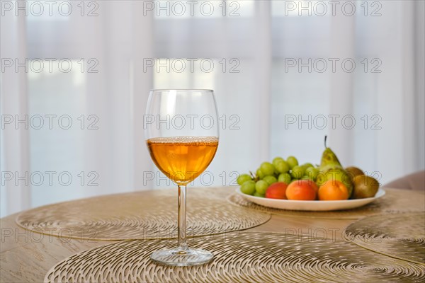 Apple juice in a wine glass on a table with fresh fruits on background