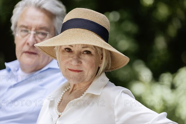 Summery dressed older woman together with her grey-haired man in the park