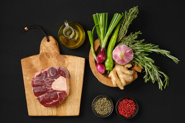 Top view of raw beef shank cross-cut on chopping board with ingredients for cooking