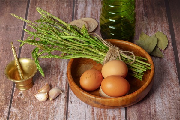 Bunch of wild asparagus in a wooden bowl with eggs